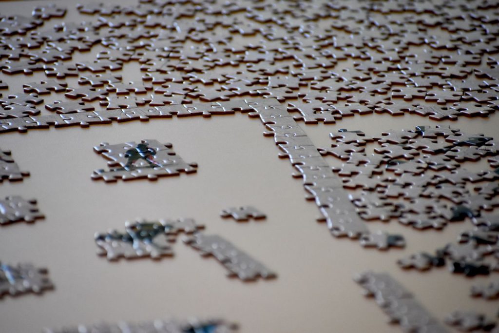 A detailed image of an incomplete jigsaw puzzle with pieces scattered on a table surface.